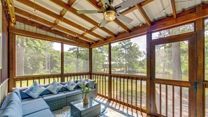 Un portico coperto con soffitto in legno, un divano con cuscini e vista sull'esterno.