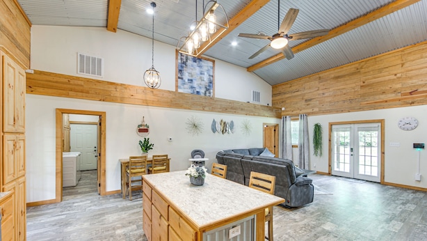 Un'ampia cucina con isola centrale, travi in legno a soffitto e una ventola a soffitto.