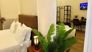 Ein Hotelzimmer mit Bett, Schreibtisch, Sessel, Fernseher und Heizkörper.