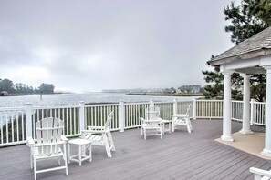 A wooden deck with white Adirondack chairs and a gazebo overlooking a body of water. - Pet-friendly Ocean View Condo w/ Community Perks! (Ocean View)