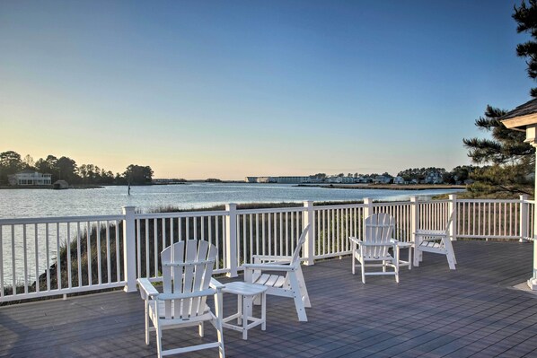 A wooden deck with white Adirondack chairs overlooking a body of water. - Pet-friendly Ocean View Condo w/ Community Perks! (Ocean View)