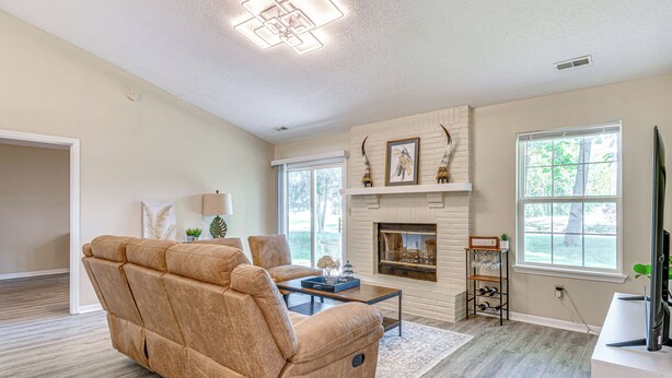 Una sala de estar con un sofá color beige, una chimenea y un televisor.