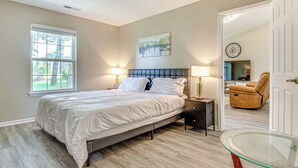 Un dormitorio con cama, lámparas de noche, una mesita de cristal y una silla.