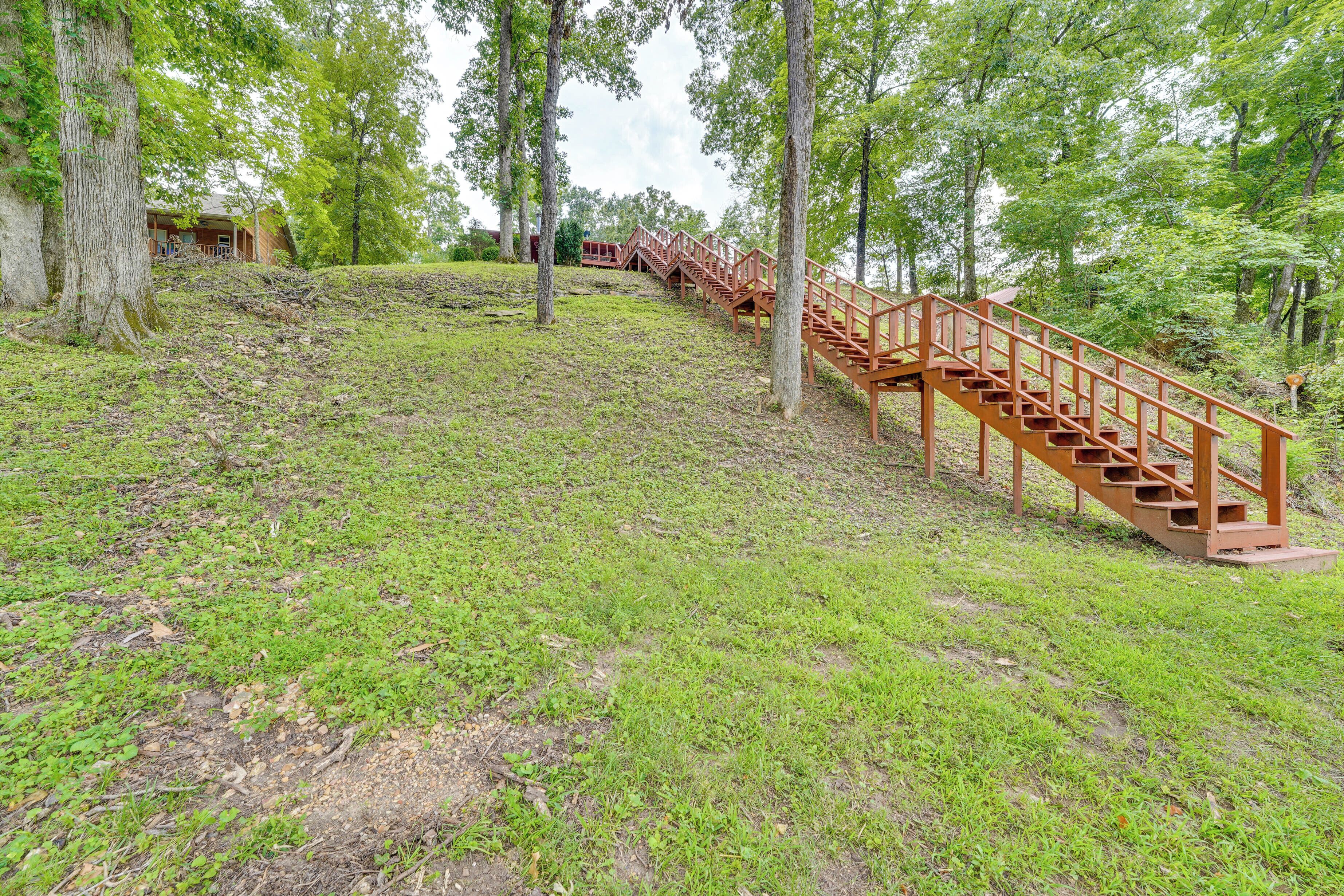 A wooden staircase leading up a grassy slope, surrounded by trees.