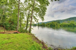 A riverbank with a wooden viewing platform, surrounded by lush greenery and trees. - Flippin Home w/ Fire Pit: Walk to White River! (Flippin)