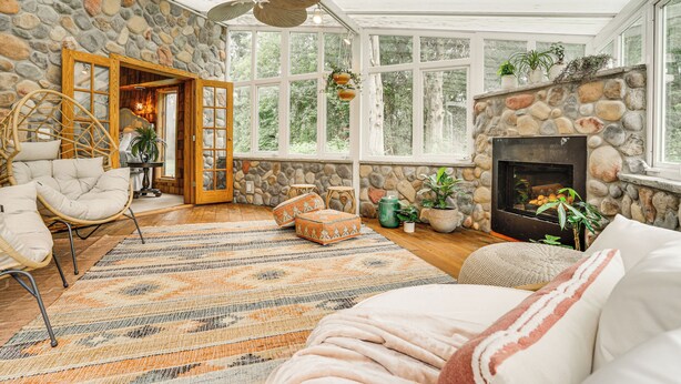 Ein gemütliches Zimmer mit Steinwand, Kamin und großem Fenster.