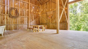 Ein rustikales Bauernhaus-Interieur mit Holzwänden, einem gewobenen Kranz, Lichterketten, einer hölzernen Bank und einem Tisch.