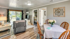 A cozy living room with a sofa, a dining table with chairs, a TV, and a window with curtains.