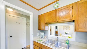 A kitchen with wooden cabinets, a stainless steel sink, and a coffee maker.