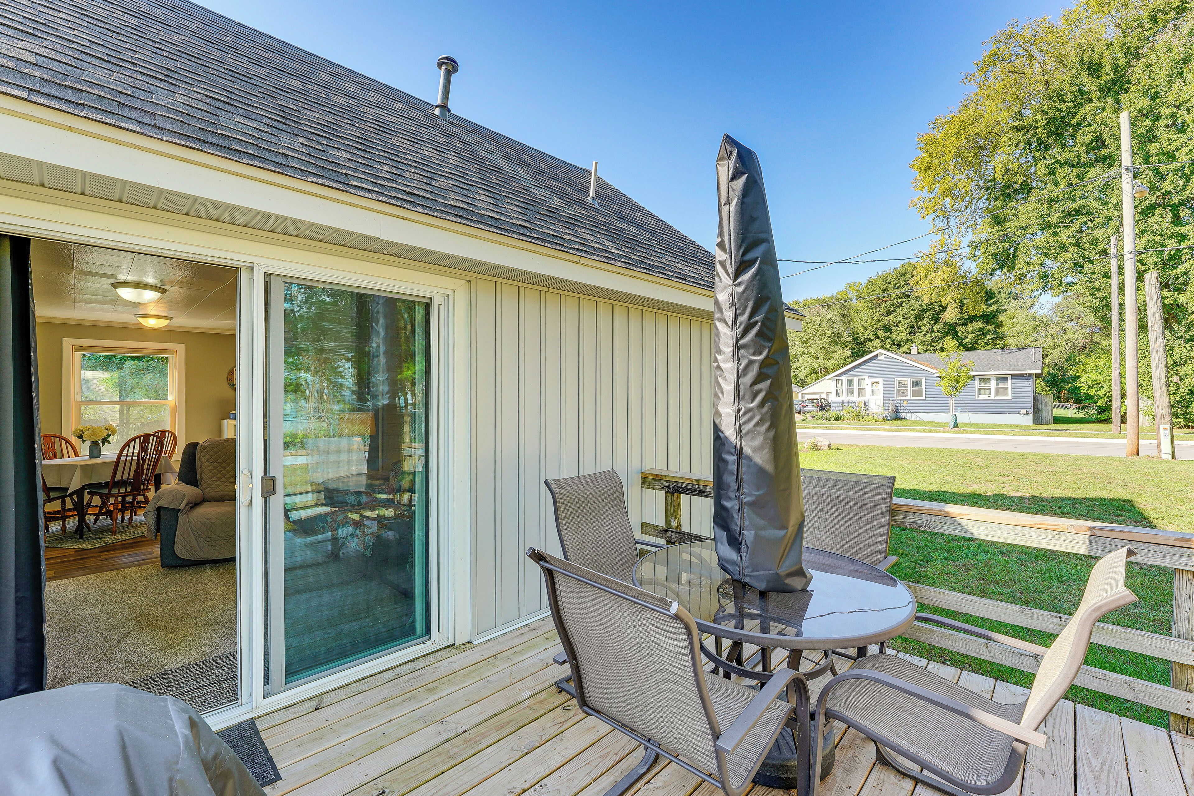 A deck with outdoor furniture, including chairs and a table, and a covered umbrella.