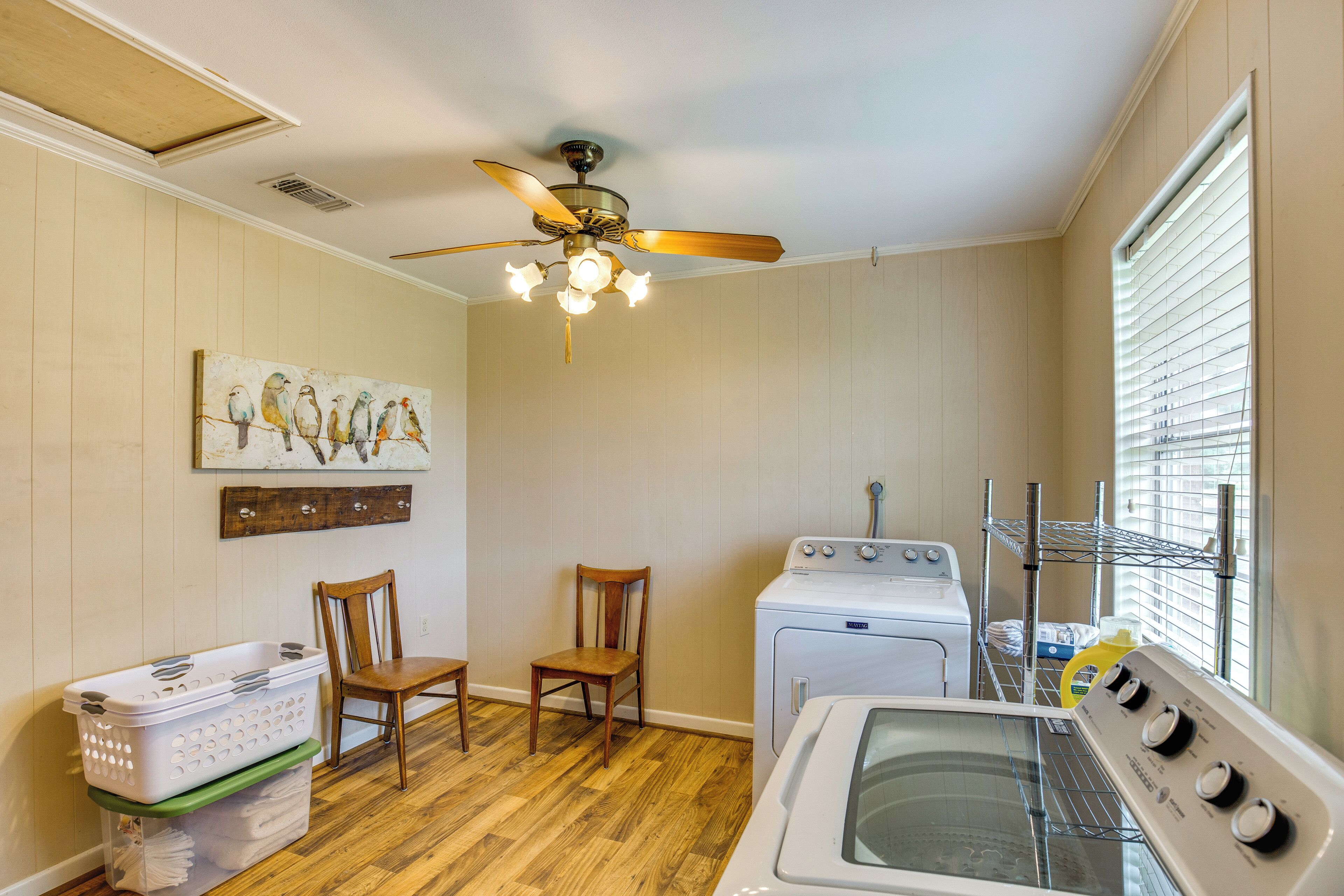 A laundry room with a ceiling fan, a washing machine, a dryer, and a wooden chair.