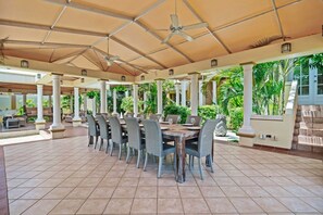 An outdoor patio with a long dining table, chairs, and umbrellas.