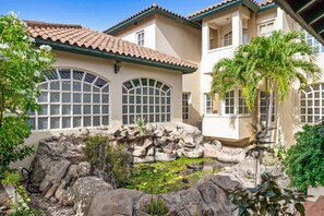 A building with a courtyard featuring a rock formation and a pond with lily pads.