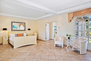A hotel room with a bed, two bedside lamps, a mirror, a window with curtains, and a small table with a plant. - Resort-Style 6BR Villa w/ Pool & Sun near Beach (Noord)