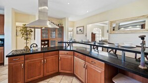 Una cocina con una isla grande, armarios de madera y una campana extractora de acero inoxidable.