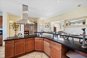 A kitchen with a large island, wooden cabinets, and a stainless steel range hood. - Resort-Style 6BR Villa w/ Pool & Sun near Beach (Noord)