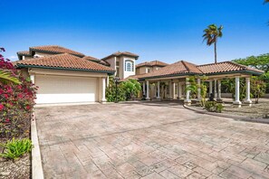 A residential property with a large driveway, a covered patio area, and a garage.
