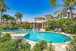 A swimming pool with a sunken center, surrounded by palm trees and lounge chairs.