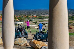 A golf course with a clear view of the landscape, including buildings and trees in the distance. - Aruba Private Pool Oasis: 5BR near Amazing Beaches (Noord)
