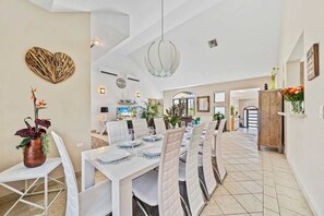 A spacious dining area with a long table set for a meal, surrounded by white chairs. - Aruba Private Pool Oasis: 5BR near Amazing Beaches (Noord)