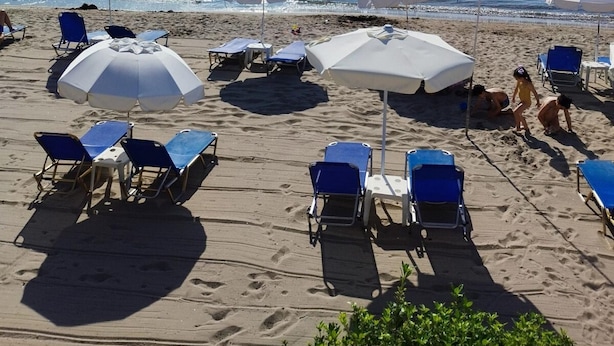 Una spiaggia con ombrelloni, lettini e una vista libera sul mare.