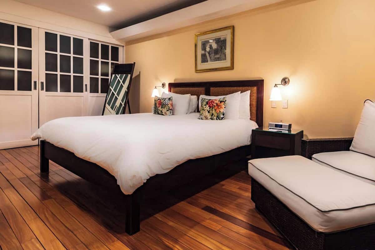 Un dormitorio con una cama grande, una silla, una mesita de noche y un armario.