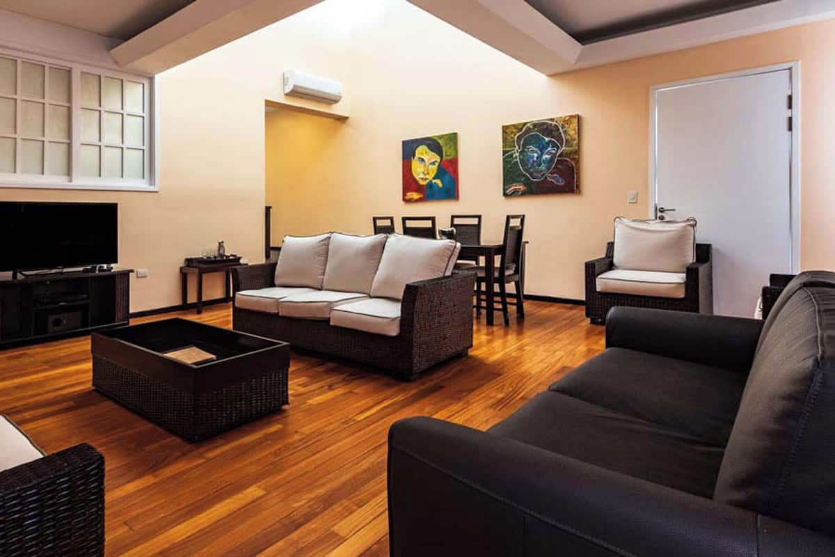 Una sala de estar con un sofá, una mesa de centro y un televisor. Hay dos cuadros en la pared.