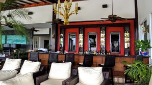 A bar area with wicker furniture and a red accent wall. - Gaia Collection Hotels - Adults only (Quepos)
