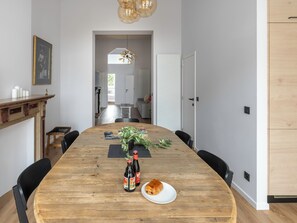 Un comedor con una mesa de madera, sillas, una planta y un plato con un pastel.