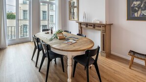 A dining room with a round wooden table, black chairs, a fireplace, and a large window with a view of buildings. - Brussels Toison D'or (Brussels)