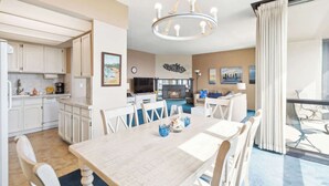 A modern hotel room with a dining area, kitchen, and a fireplace. - Sand & Sea (316) Marine Dream-Beachview with Pool (Seaside)