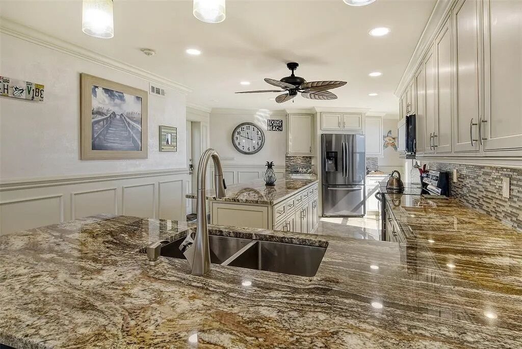 A kitchen with granite countertops, stainless steel appliances, and a ceiling fan.