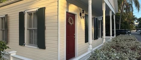 A single-story house with a porch, a red door, and a mailbox.
