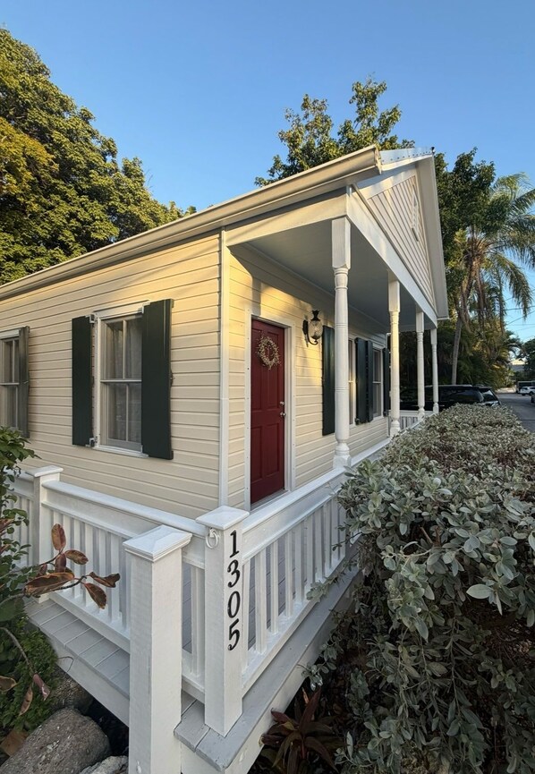 A single-story house with a porch, a red door, and a mailbox.