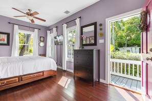 Une chambre à coucher comprenant un lit, une commode, un ventilateur de plafond et de grandes fenêtres.