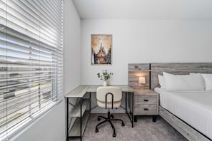 A modern hotel room with a desk, chair, and bed.