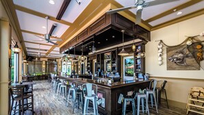 A spacious bar area with a long counter, multiple stools, and a ceiling fan. - Enhanced  Townhome! Minutes from Disney World! Resort Amenities! (Davenport)