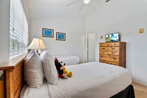 A bedroom with a bed, a dresser, a lamp, and a television.