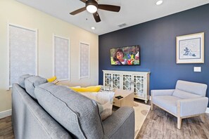 A living room with a grey sofa, a light blue armchair, a wooden coffee table, and a cabinet with glass doors. - 3BR Margaritaville Resort Townhouse, Close to WDW! (Kissimmee)