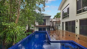 Une maison moderne dotée d’une piscine, d’une terrasse en bois et d’un escalier menant à un deuxième étage.