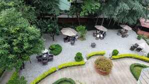 An outdoor patio area with seating arrangements, umbrellas, and landscaped garden beds.