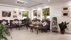 A room with ornate sofas, a coffee table, and framed pictures on the walls.