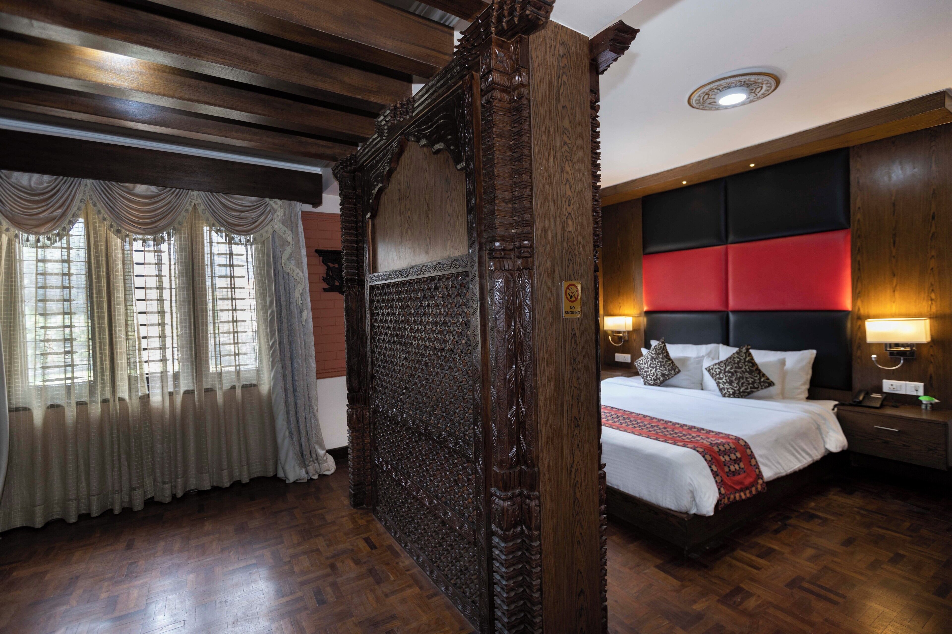 Quarto tradicional com uma cama grande, painéis de madeira e uma parede em vermelho.