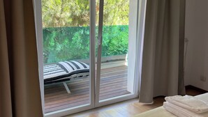 A bedroom with a large sliding glass door leading to a wooden deck.