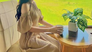 A person seated on a chair by a window overlooking a green field. - Room in House - Trang An Ao Dai Homestay - Triple Room With Field View - Bich Dong Room (Hoa Lu)