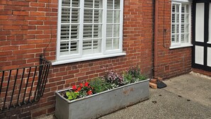 Ein rotes Backsteinhaus mit weißen Fensterrahmen und einem kleinen Blumenbeet.