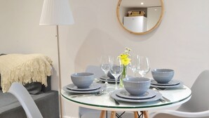 A dining table set with blue bowls, plates, and wine glasses, a lamp, and a mirror on the wall. - New Flat near Luton Airport *FREE Parking* (Luton)