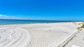 A wide sandy beach with a clear blue sky and calm sea.