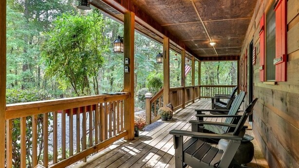 Une véranda en bois avec des fauteuils à bascule, une balustrade en bois et une vue sur une forêt.