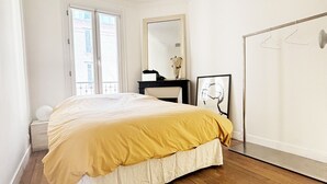 Une chambre à coucher comprenant un lit, une commode, un miroir et une armoire.